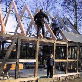Sanieren eines alten Fachwerkgebäudes nach einem Brand. Hier wird altes Eichenkant- holz an den zerstörten Bereichen des Fachwerks eingesetzt und der Dachstuhl komplett neu aufgebaut.